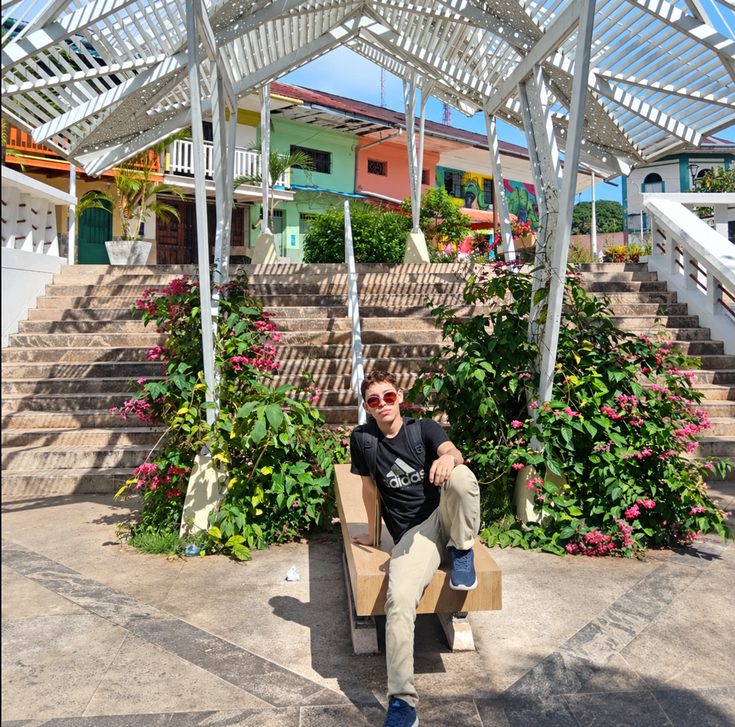 El Semental Oriental sentado en una plaza, bajo una pérgola y junto a flores